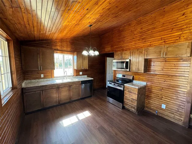 a large kitchen with stainless steel appliances wooden floors and wooden cabinets