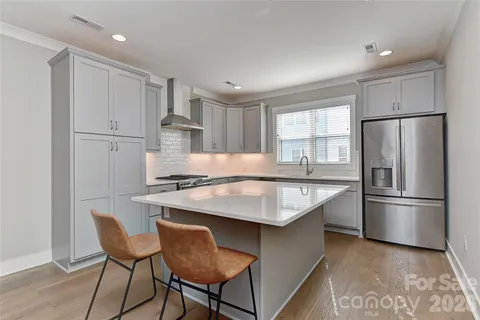 a kitchen with stainless steel appliances granite countertop a dining table chairs refrigerator and window