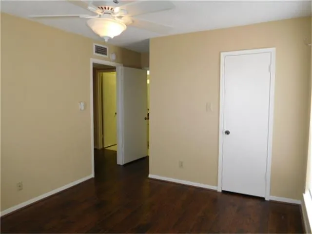 an empty room with wooden floor and a ceiling fan
