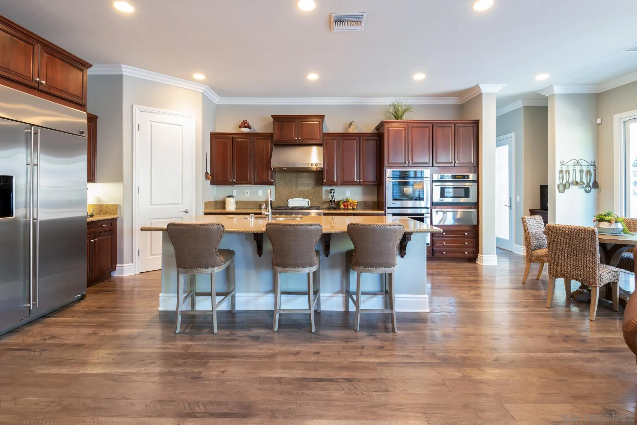 3234 Corte Aliso Carlsbad, CA 92009 - Photo 5 of 44 a kitchen with stainless steel appliances kitchen island granite countertop a dining table chairs and a refrigerator