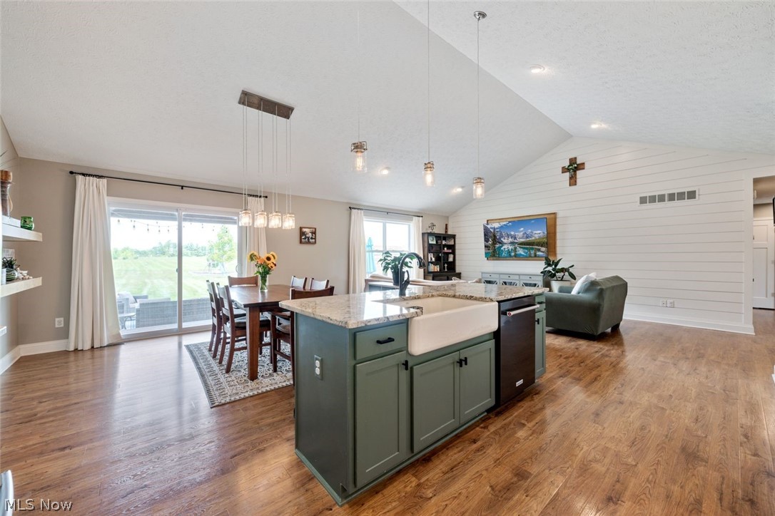 6517 Stone Road Medina, OH 44256 - Photo 18 of 47 Kitchen with decorative light fixtures, stainless steel dishwasher, hardwood / wood-style floors, light stone counters, and a center island with sink
