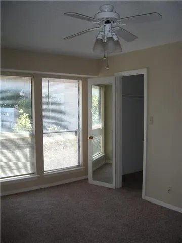 an empty room with windows and fan