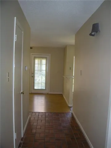 a view of a hallway with wooden floor and a bathroom