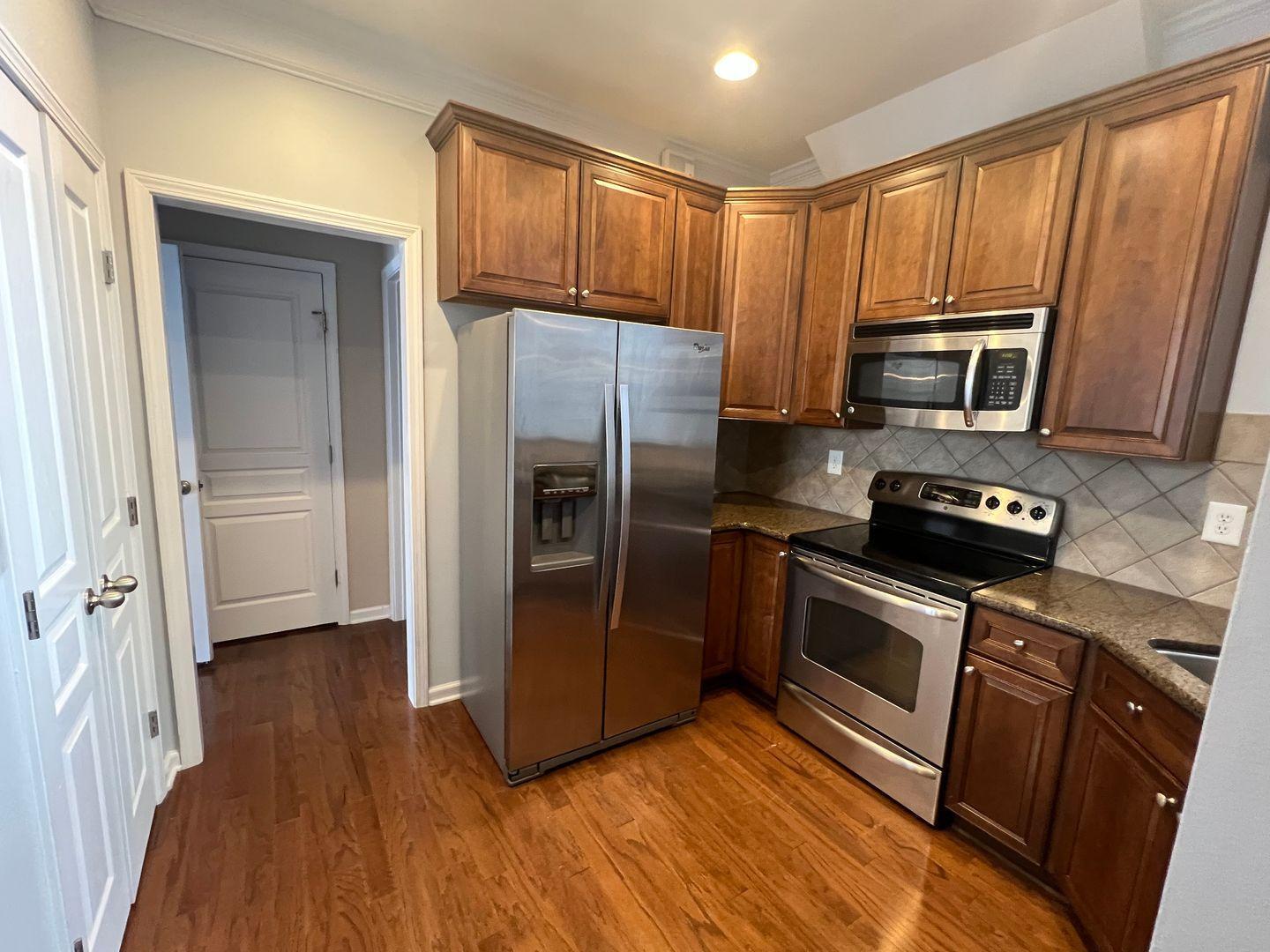 10117 Falls Meadow Court Raleigh, NC 27617 - Photo 13 of 34 a kitchen with granite countertop wooden floors stainless steel appliances and a window