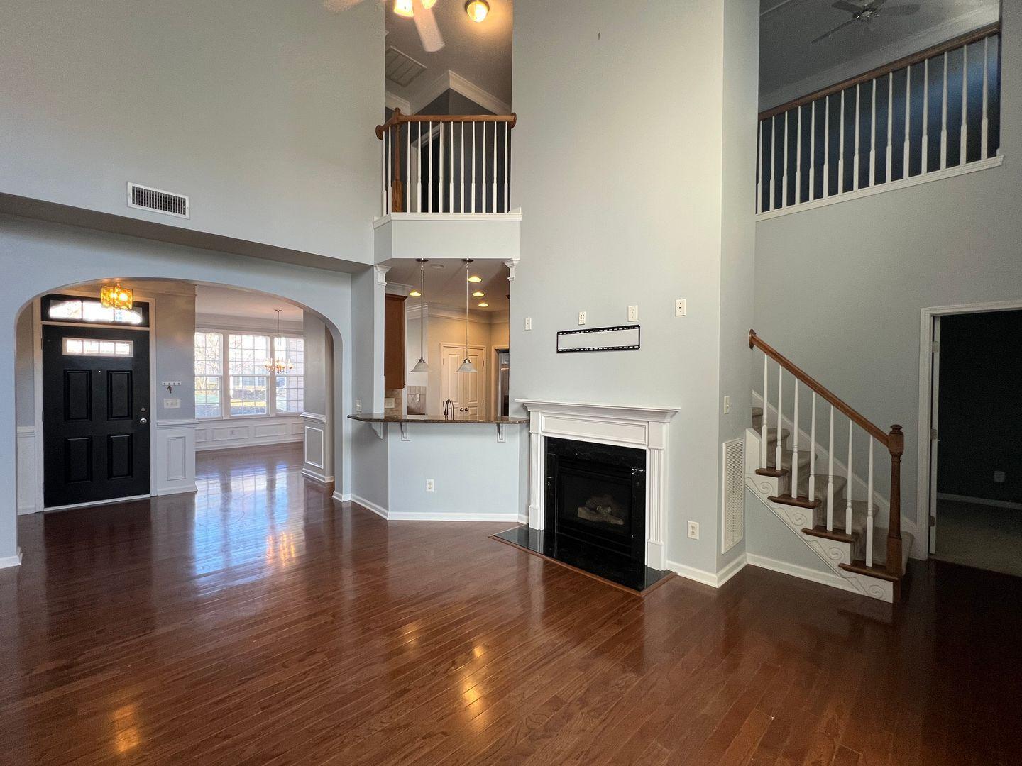 10117 Falls Meadow Court Raleigh, NC 27617 - Photo 7 of 34 an entryway and a livingroom with wooden floor stairs