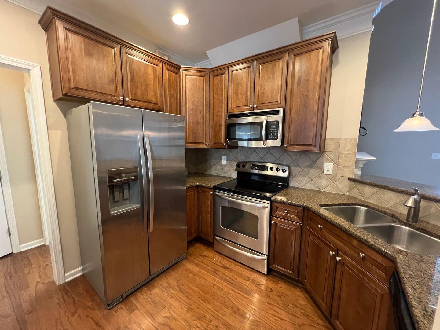 10117 Falls Meadow Court Raleigh, NC 27617 - Photo 10 of 34 a kitchen with granite countertop a refrigerator a sink a stove a microwave and wooden cabinets