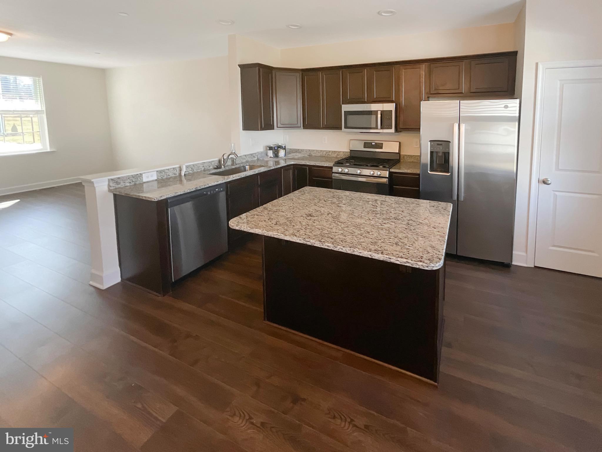 109 Holstein Drive Hanover, PA 17331 - Photo 7 of 26 a kitchen with stainless steel appliances granite countertop a sink a stove a refrigerator and island with wooden floors