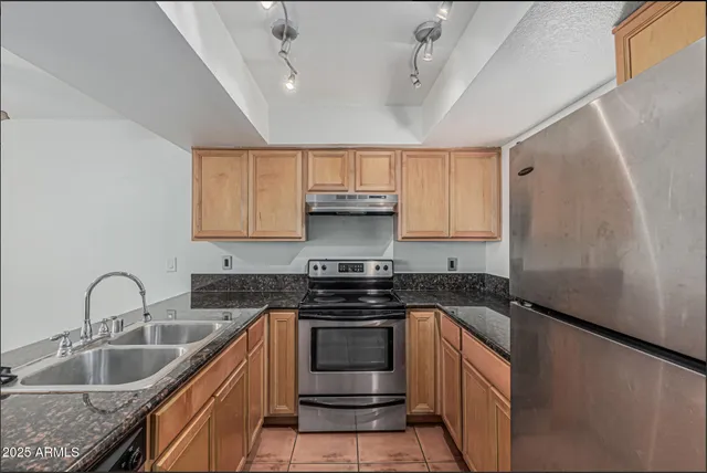 a kitchen with granite countertop a sink stove and refrigerator