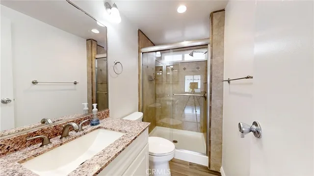 a bathroom with a granite countertop sink toilet mirror and shower