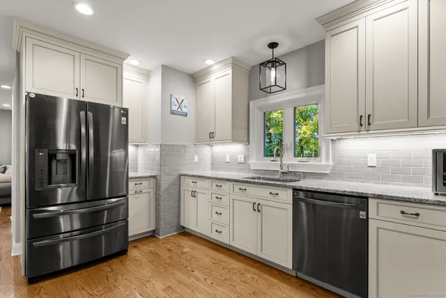 a kitchen with granite countertop stainless steel appliances a refrigerator cabinets and a sink