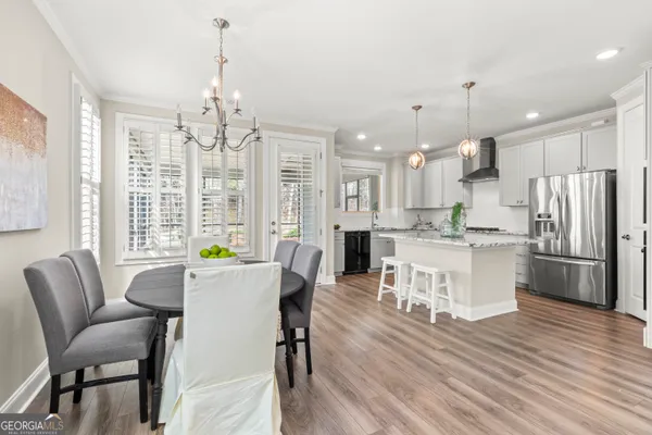 a kitchen with stainless steel appliances kitchen island granite countertop a table chairs and a refrigerator