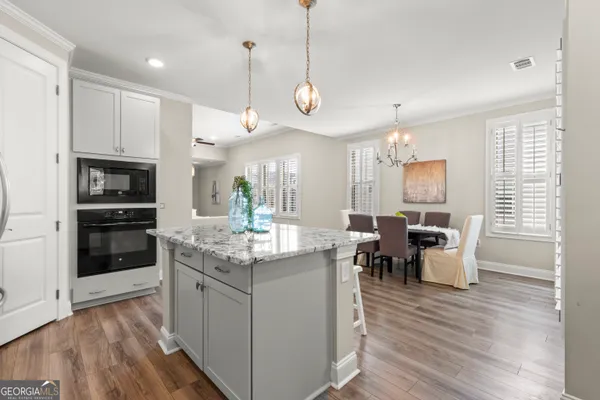 a kitchen with stainless steel appliances granite countertop a stove a refrigerator a kitchen island a sink dishwasher a dining table and chairs with wooden floor