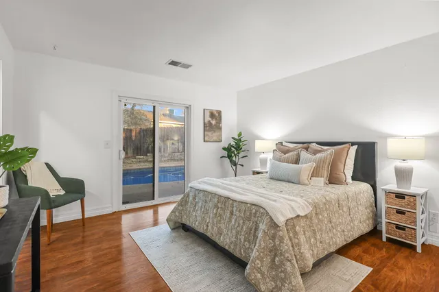 a spacious bedroom with a bed and wooden floor