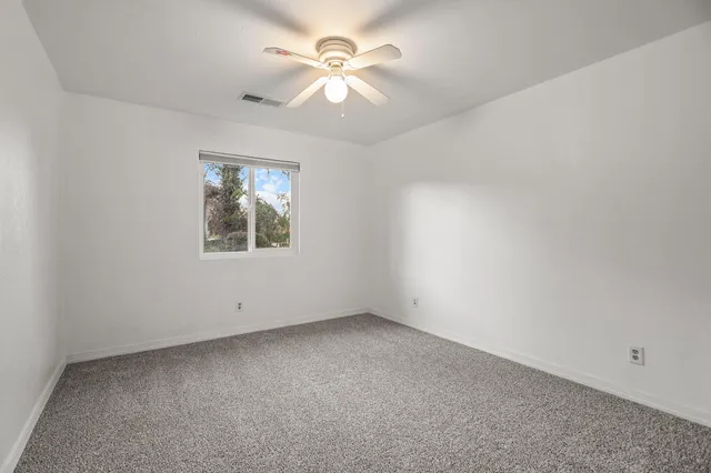 an empty room with windows and fan