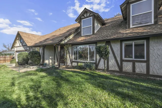 a view of a brick house with a big yard and large trees