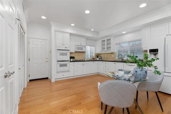 a kitchen with white cabinets and chairs