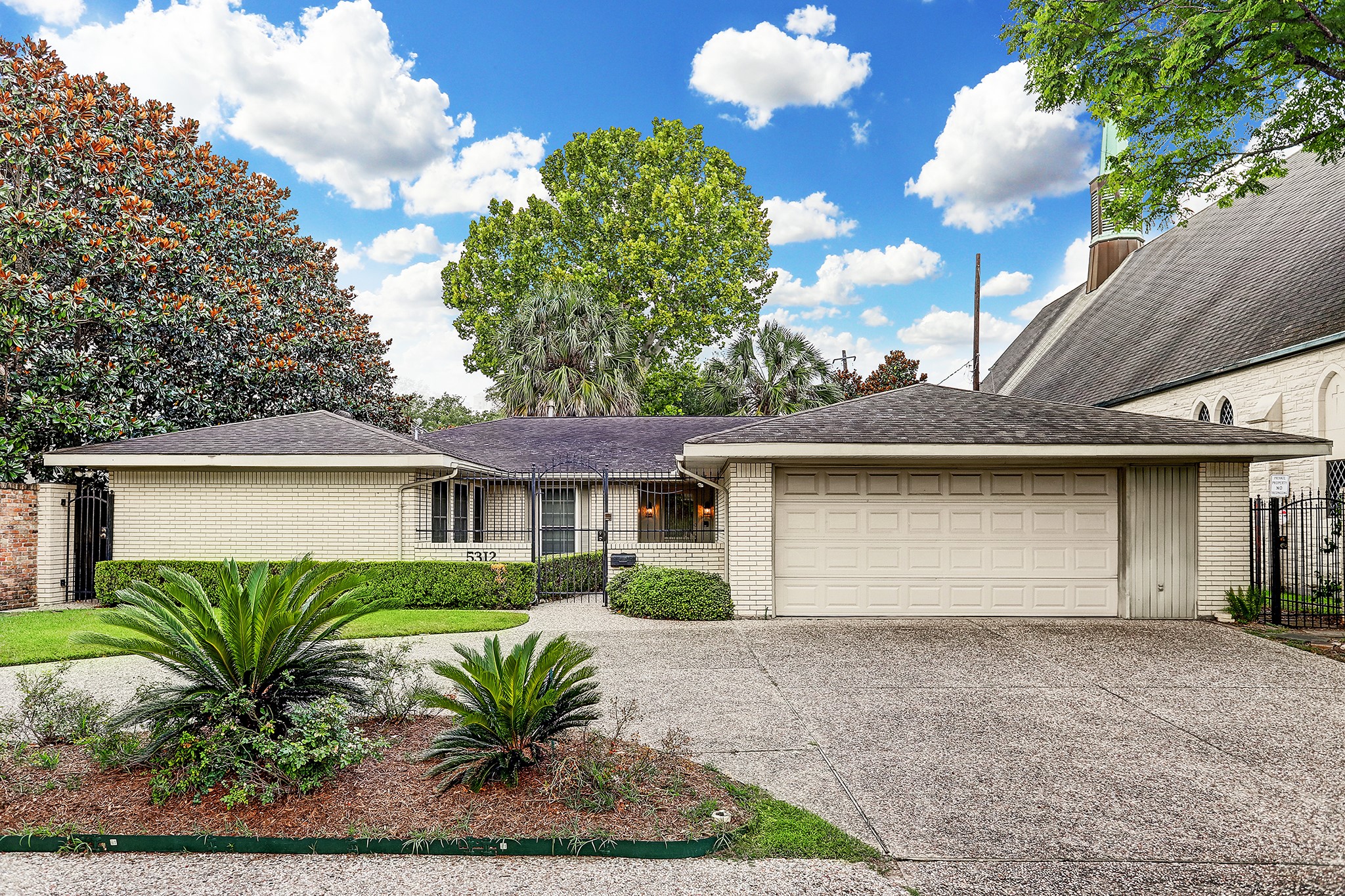 Ranch style, brick home with gated courtyard, 2-car garage, and a circular driveway for extra parking.