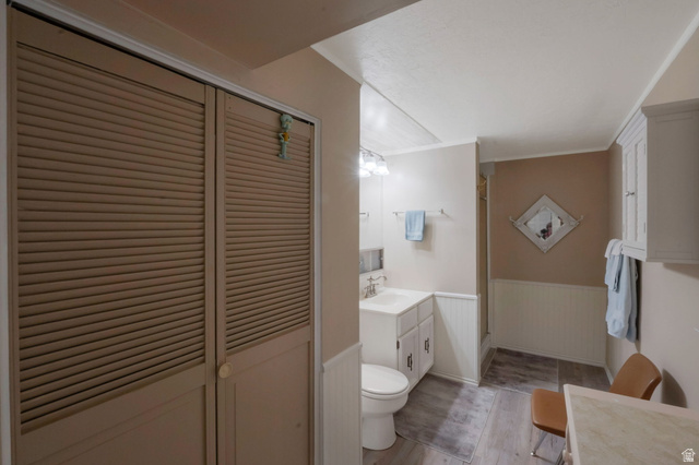 11072 Windy Peak Ridge Drive, Unit 32 Sandy, UT 84094 - Photo 29 of 30 Bathroom featuring a single vanity with a white cabinet, a toilet, a shower stall, and wood-finish flooring