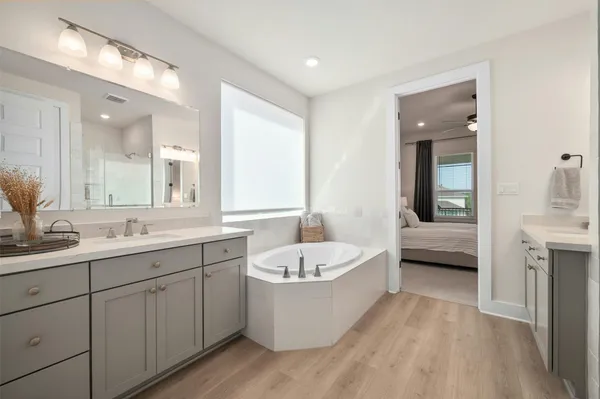 a spacious bathroom with a tub sink and mirror
