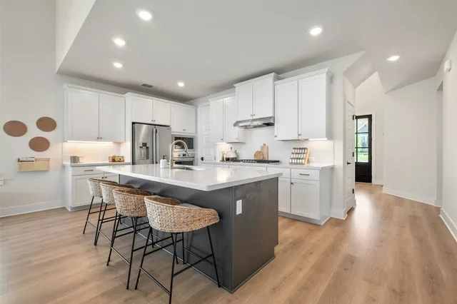 a kitchen with stainless steel appliances granite countertop a white cabinets and wooden floor