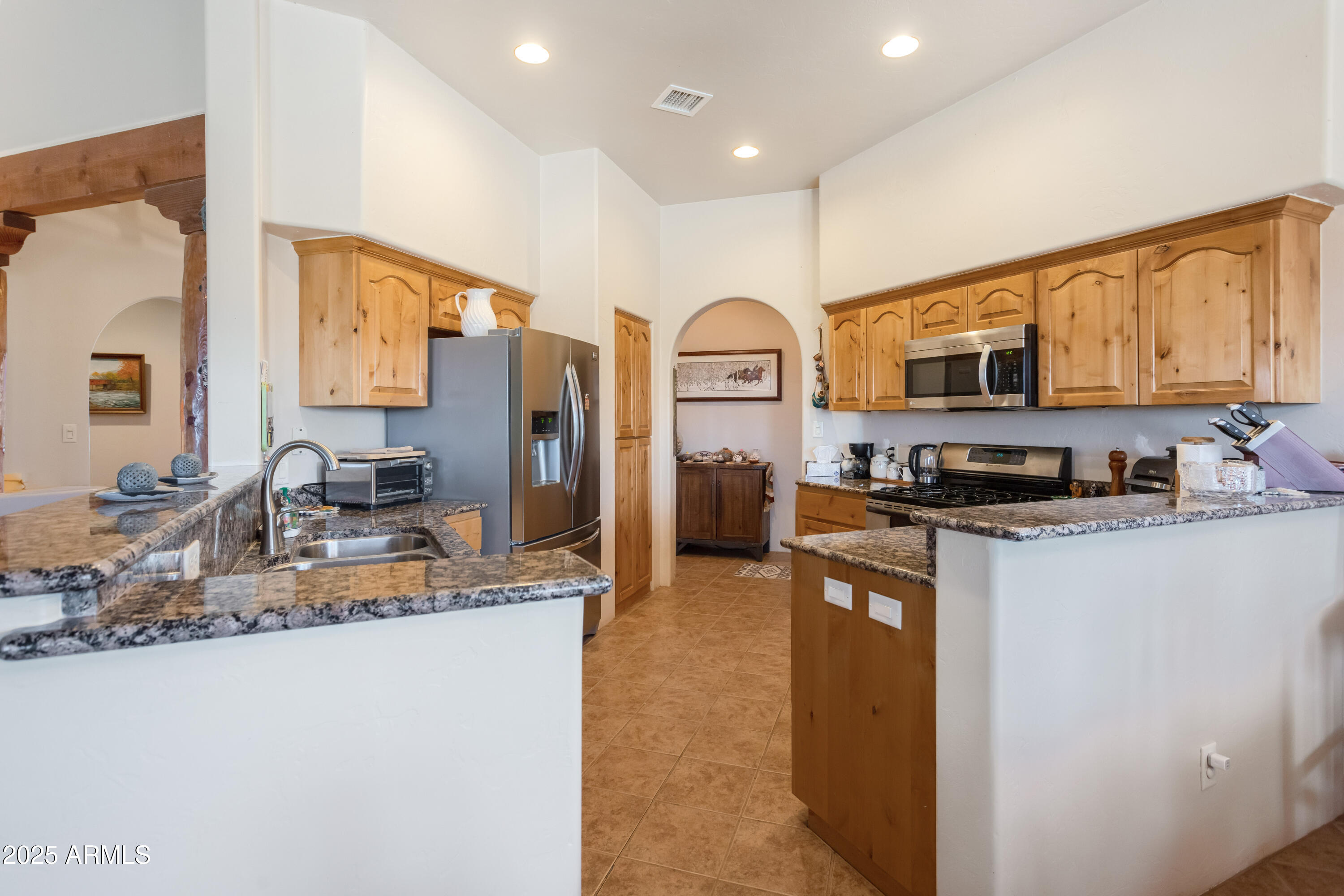 8765 South Airstrip Road Hereford, AZ 85615 - Photo 15 of 47 a kitchen with stainless steel appliances granite countertop a stove top oven a sink and a refrigerator