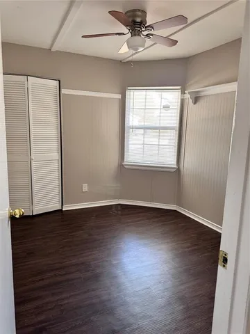 an empty room with wooden floor chandelier fan and windows