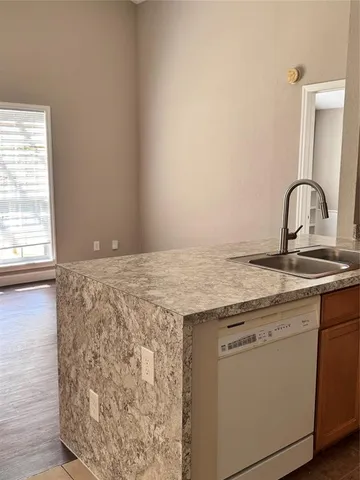 a view of a kitchen with a sink and dishwasher with wooden floor