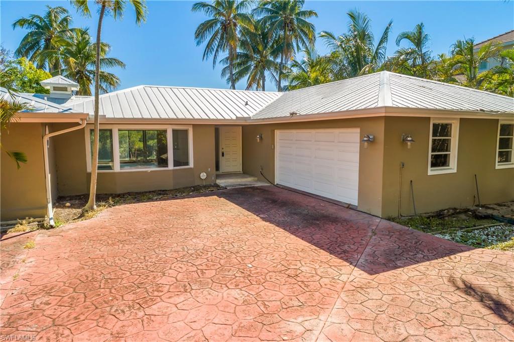 2195 Sheepshead Drive Naples, FL 34102 - Photo 2 of 14 a front view of a house with a yard and garage