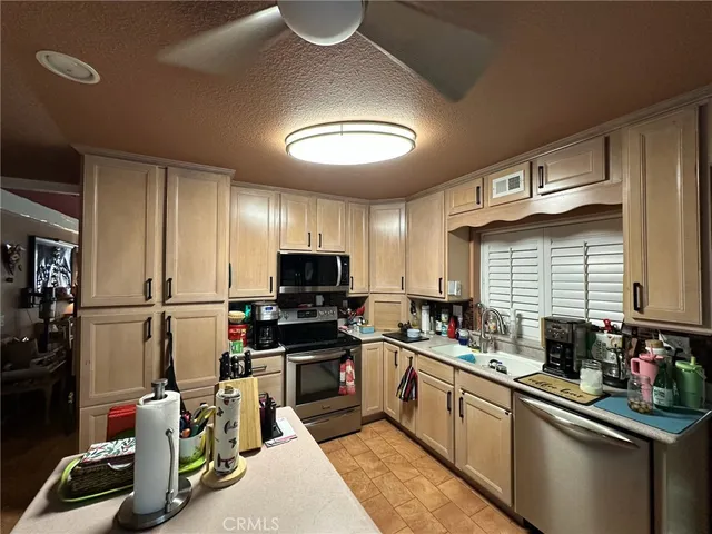 a kitchen with stainless steel appliances a sink a stove a refrigerator cabinets and a window