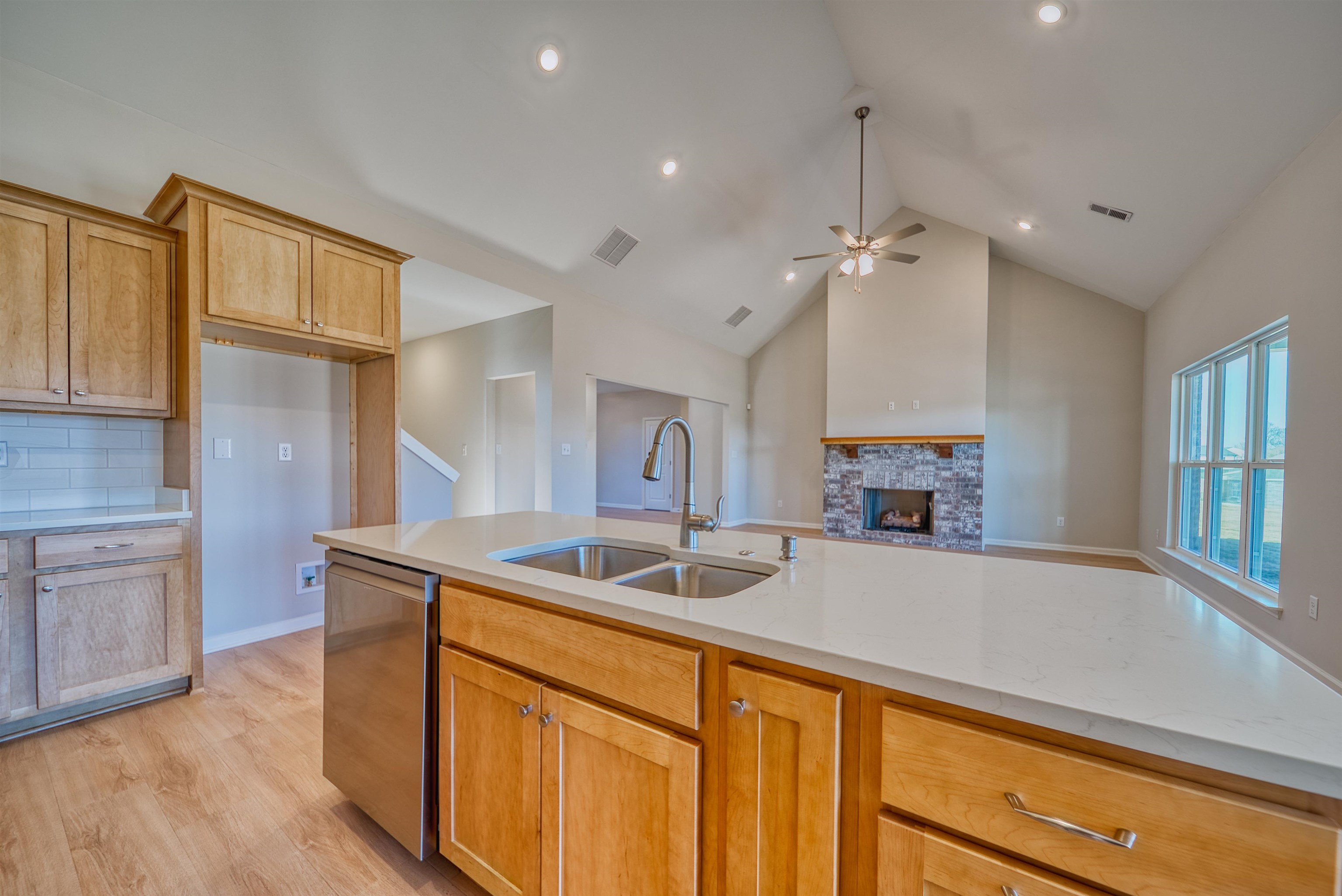 196 Como Lane Atoka, TN 38004 - Photo 13 of 40 Kitchen featuring a lit fireplace, stainless steel dishwasher, light wood-style floors, a ceiling fan, and light stone counters