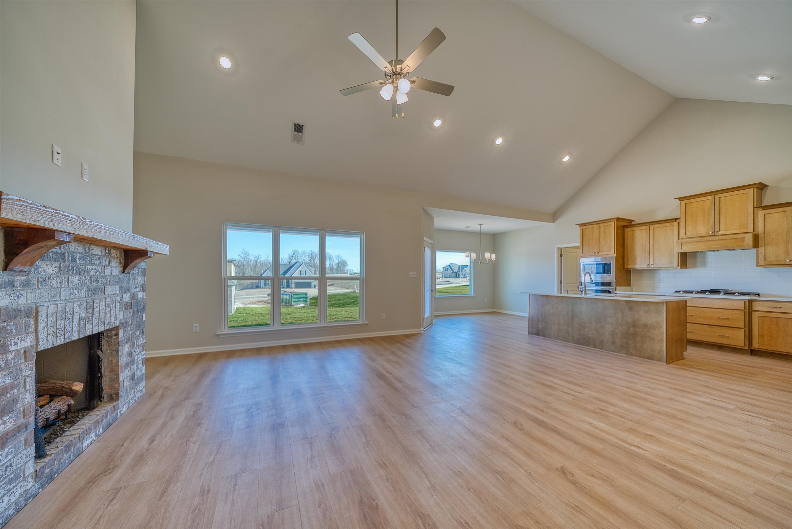 196 Como Lane Atoka, TN 38004 - Photo 5 of 40 Unfurnished living room featuring a high ceiling, ceiling fan, light wood finished floors, a fireplace, and a chandelier