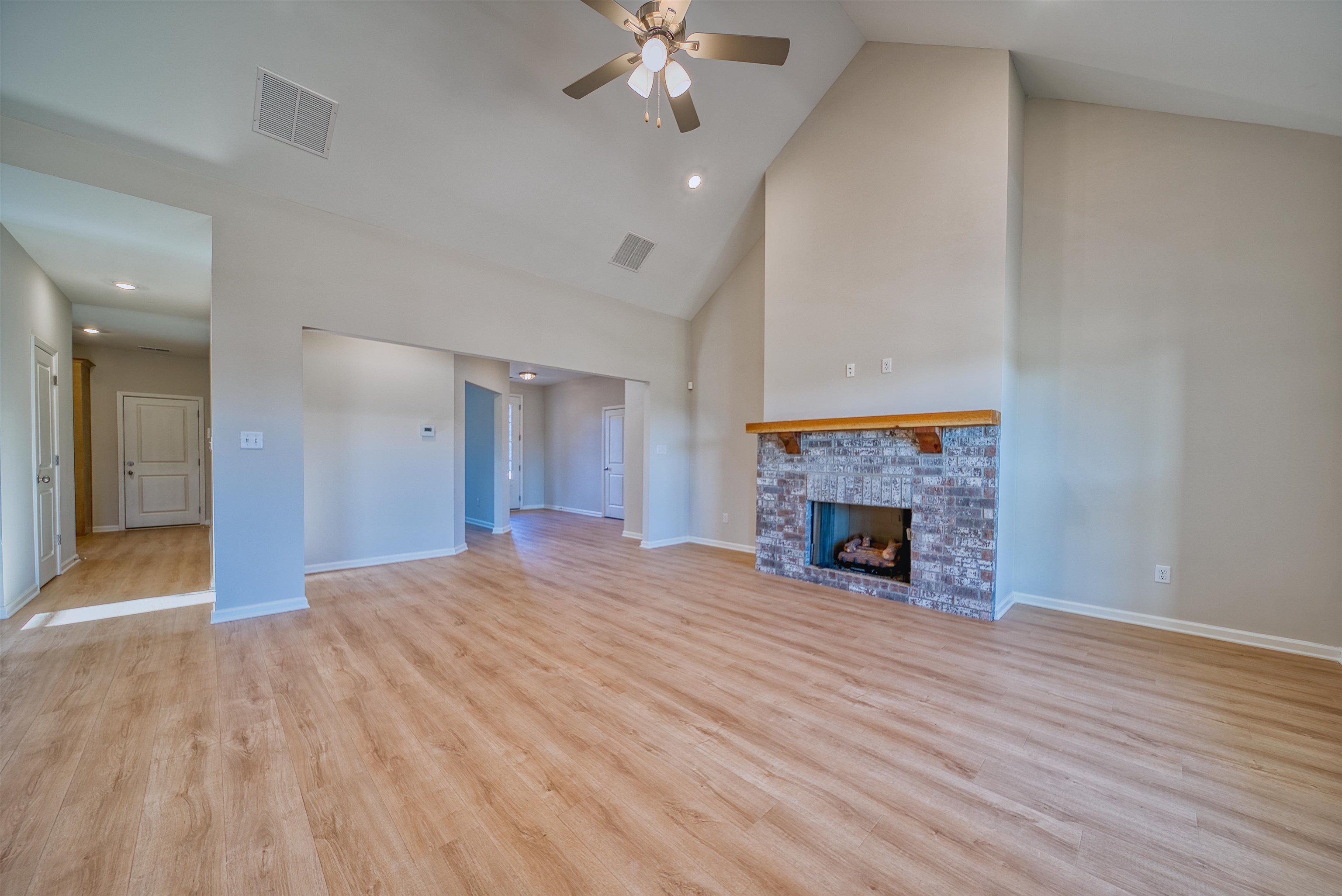 196 Como Lane Atoka, TN 38004 - Photo 6 of 40 Unfurnished living room featuring light wood-style flooring, ceiling fan, recessed lighting, a fireplace, and vaulted ceiling