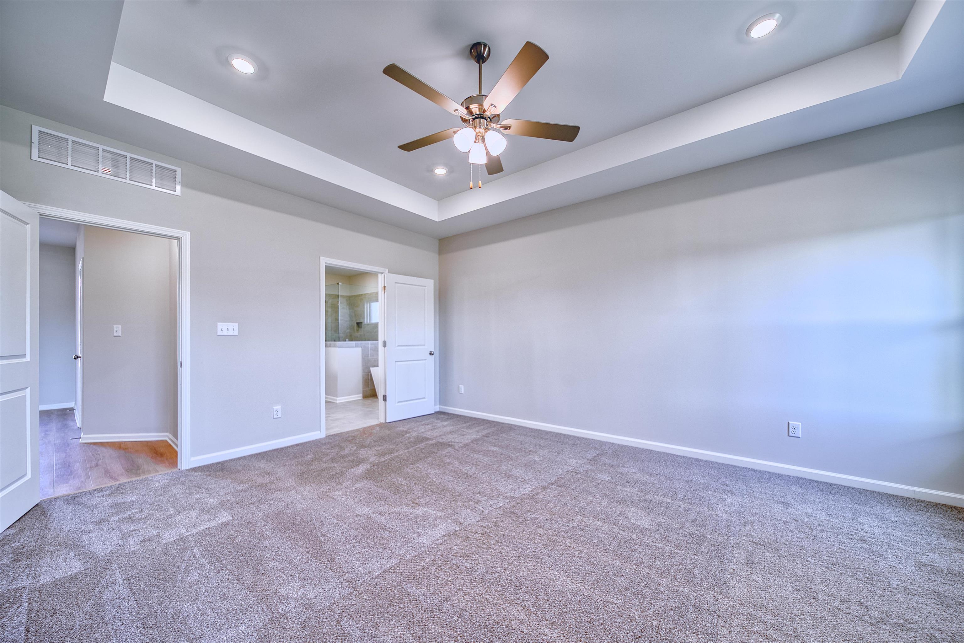 196 Como Lane Atoka, TN 38004 - Photo 8 of 40 Unfurnished bedroom with a tray ceiling, carpet flooring, ensuite bath, recessed lighting, and ceiling fan