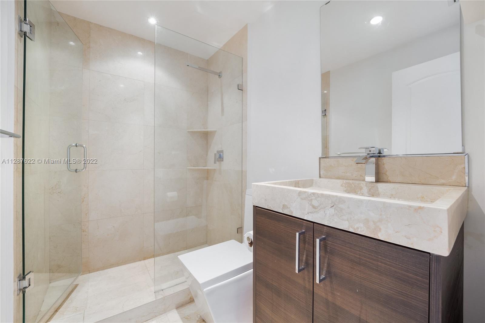 888 Brickell Key Drive, Unit 1508 Miami, FL 33131 - Photo 7 of 12 a bathroom with a granite countertop sink a toilet and shower