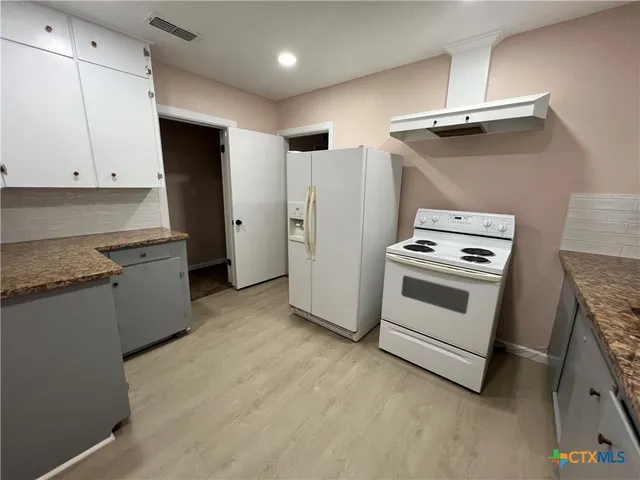 a kitchen with granite countertop a sink a stove and cabinets