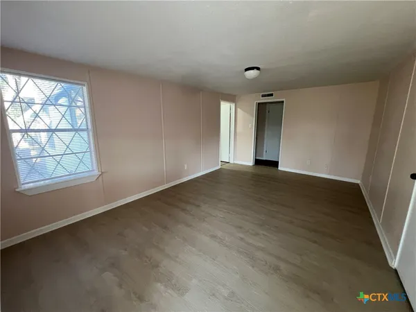 an empty room with windows and fan