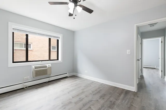 a view of an empty room with a window and wooden floor