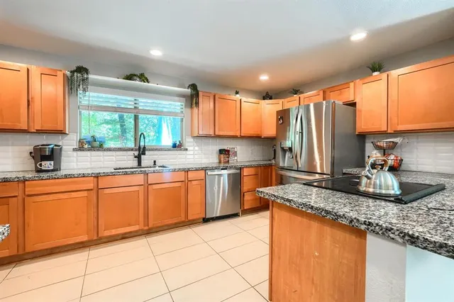 a kitchen with granite countertop a sink stainless steel appliances and cabinets