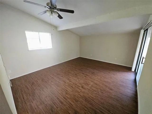 an empty room with wooden floor fan and windows