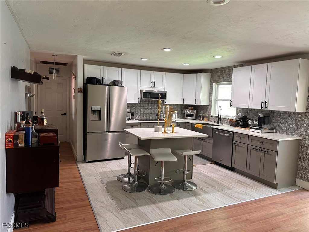 120 Rowland Road Lehigh Acres, FL 33936 - Photo 4 of 21 a kitchen with stainless steel appliances kitchen island granite countertop a refrigerator a stove a sink a dining table and chairs with wooden floor