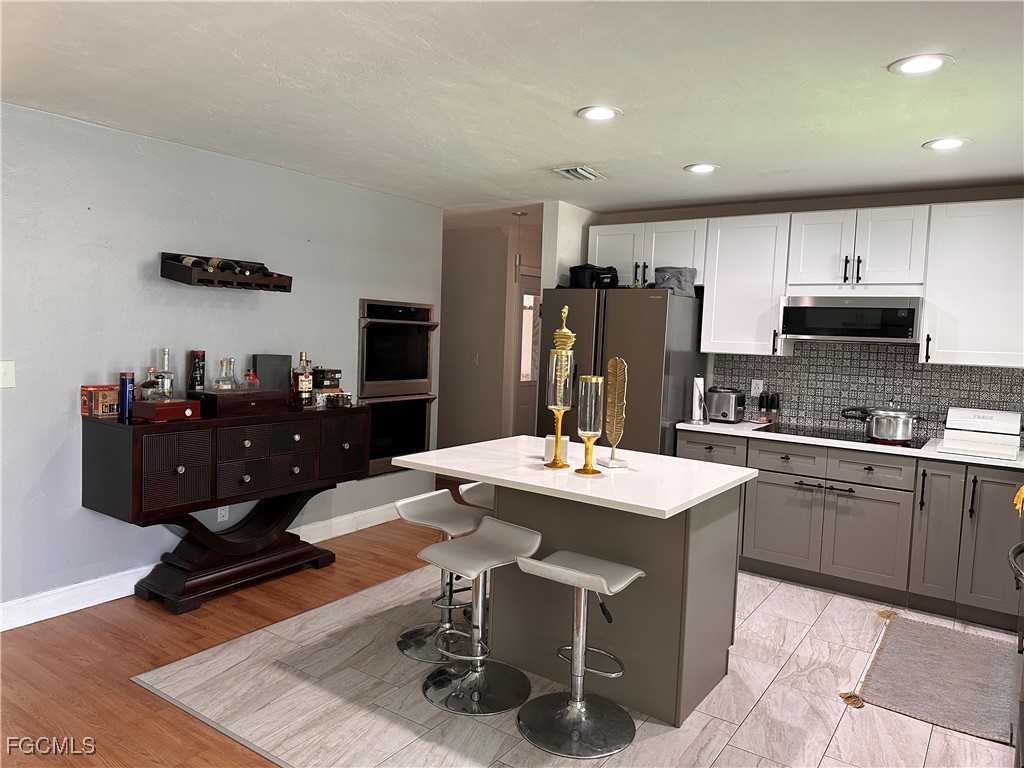 120 Rowland Road Lehigh Acres, FL 33936 - Photo 5 of 21 a kitchen with stainless steel appliances kitchen island granite countertop a refrigerator a stove a sink a dining table and chairs with wooden floor