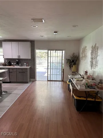 a living room with stainless steel appliances granite countertop a stove and a wooden floors