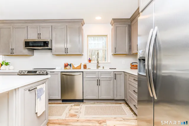 a kitchen with stainless steel appliances kitchen island granite countertop a refrigerator sink and white cabinets