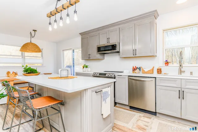 a kitchen with stainless steel appliances a white table chairs and a window
