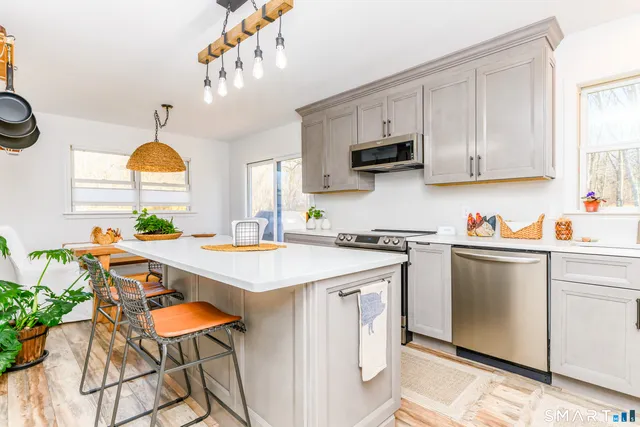 a kitchen with stainless steel appliances granite countertop a stove a sink dishwasher and white cabinets with wooden floor