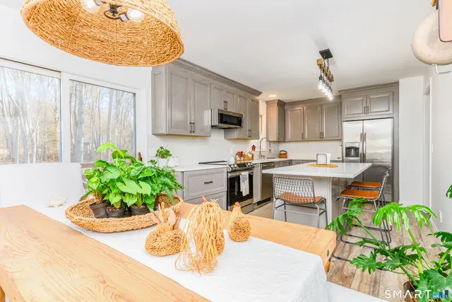 a kitchen with stainless steel appliances kitchen island granite countertop a sink a stove and a wooden floors