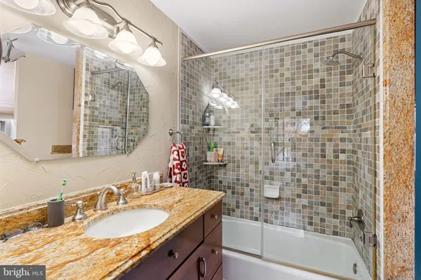 a bathroom with a granite countertop sink a mirror and a shower
