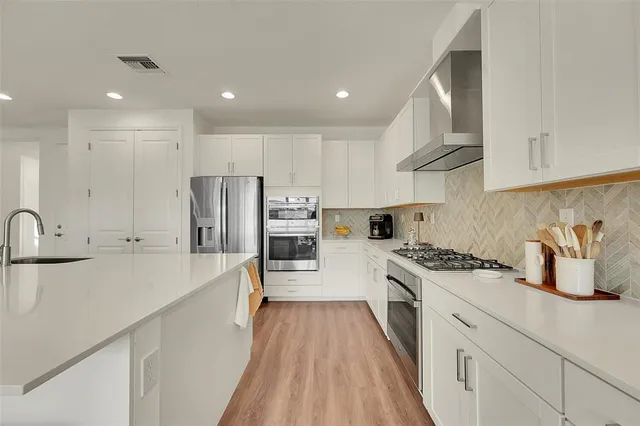 a kitchen with stainless steel appliances a sink a stove a refrigerator and cabinets