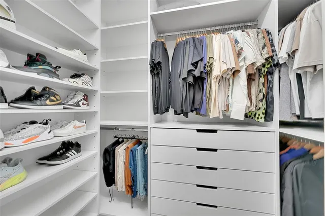 a view of walk in closet with clothes and shoes