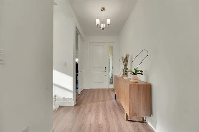 a view of a hallway with wooden floor and a chandelier